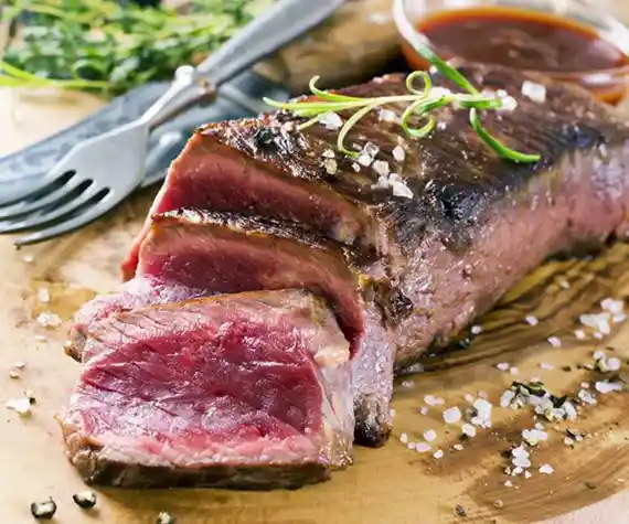 Rôti de bœuf découpé sur une planche en bois au restaurant La Table de Trois à Bordeaux