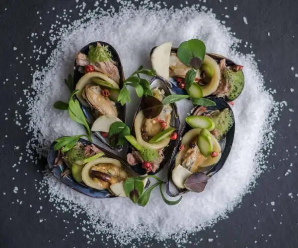 Des moules cuisinées avec des condiments déposées sur un lit de sel au restaurant La Table de 3 à Bordeaux