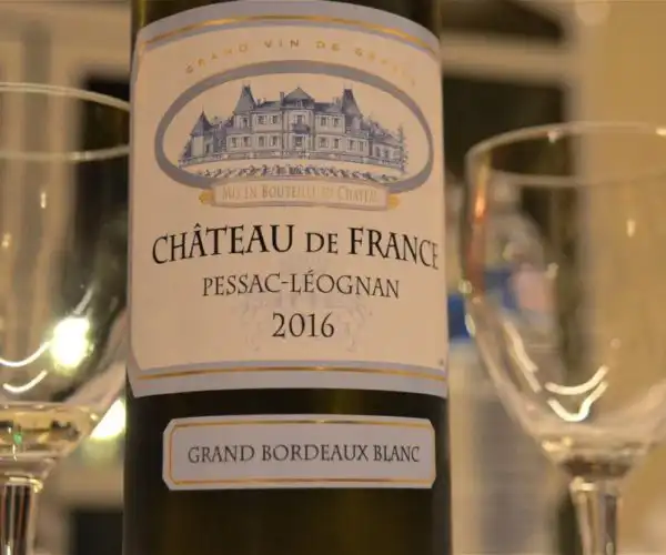 Une bouteille de vin rouge Château de France Pessac-Leognan 2016 entourée de verres au restaurant La Table de 3 à Bordeaux